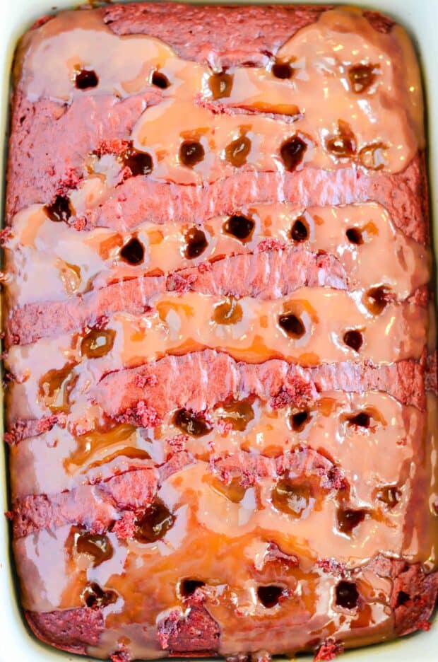Red Velvet cake soaked in caramel sundae sauce, smothered in whipped topping and decked to the hilt with chopped pecans, chocolate chips, hot fudge, and more caramel! This cake is a red velvet lovers dream come true.