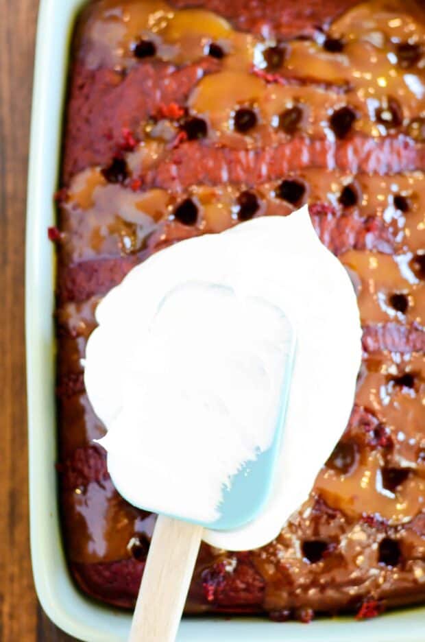Red Velvet cake soaked in caramel sundae sauce, smothered in whipped topping and decked to the hilt with chopped pecans, chocolate chips, hot fudge, and more caramel! This cake is a red velvet lovers dream come true.