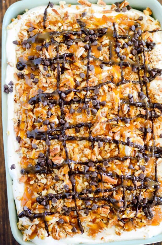 Red Velvet cake soaked in caramel sundae sauce, smothered in whipped topping and decked to the hilt with chopped pecans, chocolate chips, hot fudge, and more caramel! This cake is a red velvet lovers dream come true.
