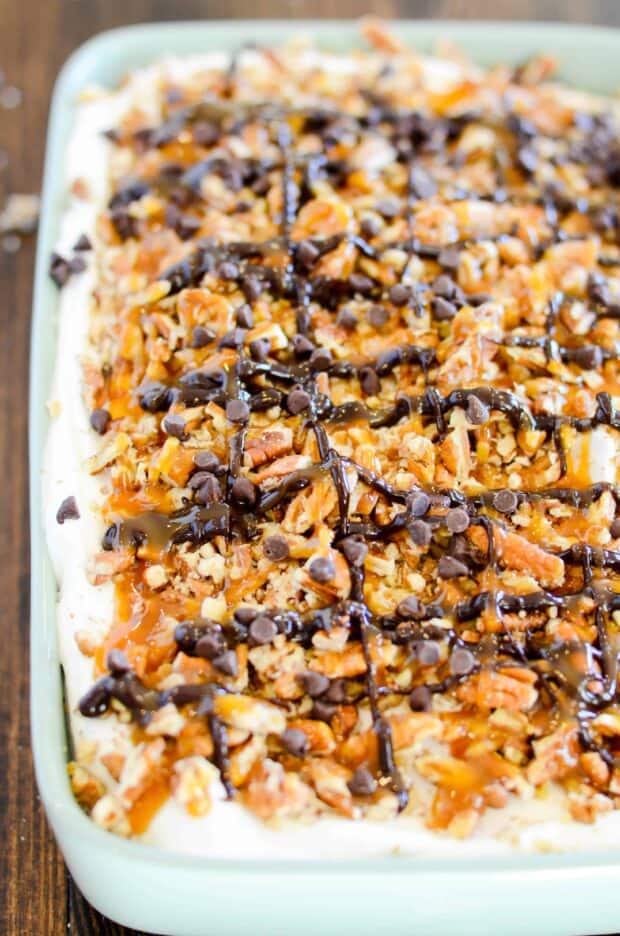 Red Velvet cake soaked in caramel sundae sauce, smothered in whipped topping and decked to the hilt with chopped pecans, chocolate chips, hot fudge, and more caramel! This cake is a red velvet lovers dream come true.