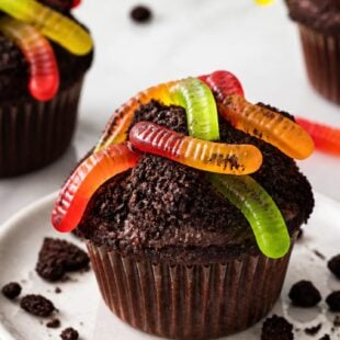 Dirt Cupcakes are the most fun spring dessert EVER — chocolate cupcakes dipped in Oreo crumbs with a candy strawberry carrot on top! 🌱