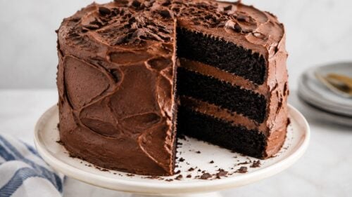 This black velvet cake is fudgy, moist & dramatically dark! Easy from-scratch recipe with black cocoa & dreamy frosting. You'll be obsessed!